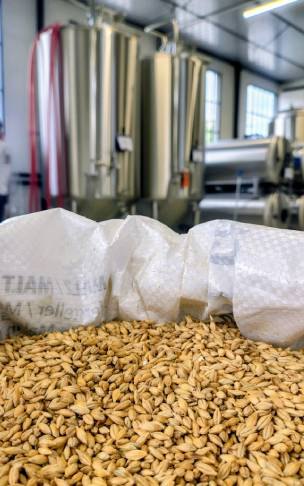 Sacchi di malto davanti ai fermentatori del birrificio
